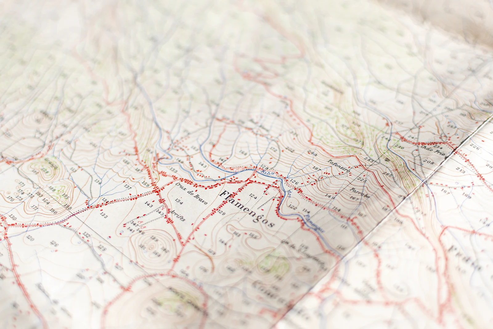 Close-up of a topographic paper map with red roads and contour lines