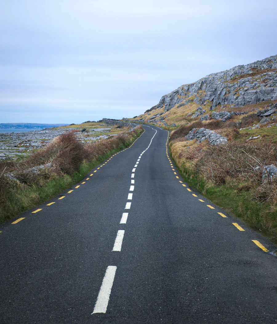 A narrow country road winding past rocky hills